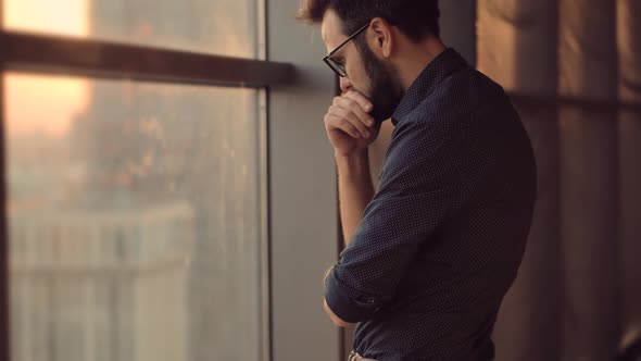 Disappointed Businessman Looking Out Of Window. Creative Man Standing Near Windows In Office. alt