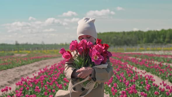 Girl with a bouquet of flowers on a tulips field