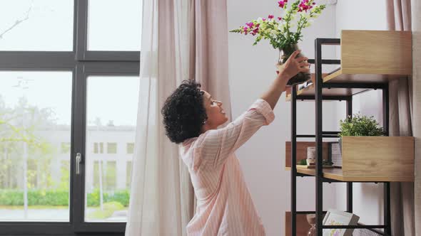 Woman Putting Flowers on Shelving at Home