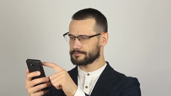 Young Handsome Businessman Is Viewing a News Feed on His Smartphone