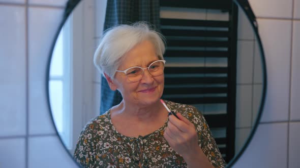 Senior Greyhaired Woman Brushing Her Hair and Looking at Her Reflection in the Mirror alt