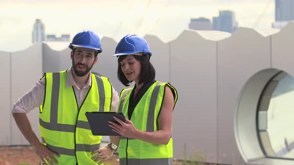 Man and woman discussing with digital tablet at construction site