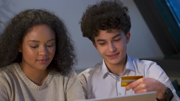 Happy Attractive AfricanAmerican a Young Couple of Zoomers Shopping Online the Guy Helps the Girl
