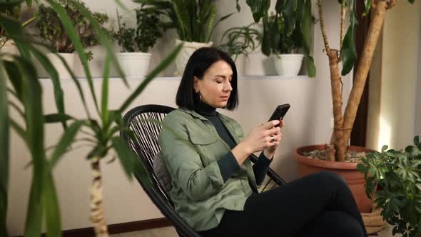 Woman Chatting Using Smartphone Sitting on Armchair at Home