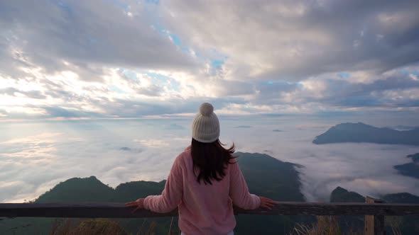 Young woman travelers looking at the sunrise and the sea of mist on the mountain alt