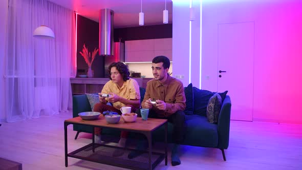 Smiling Diverse Male Friends with Gamepads Playing Video Game at Home. Portrait of Latin and alt