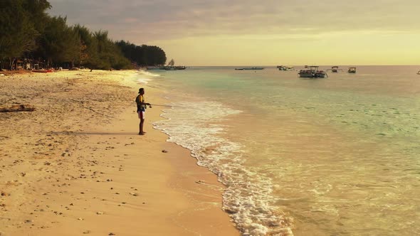 Man alone fishing alone on marine bay beach wildlife by blue lagoon and clean sand background of Bal alt