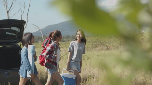 Group of a young teen Asian women helps to hold backpacks and ice coolers with friends camping.