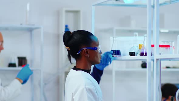 African Woman Chemist Researcher Using Glass Equipment in Lab alt