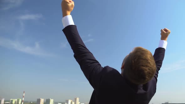 Confident Male in Suit Showing Yes Gesture Raising Hands Up Outdoors, Success