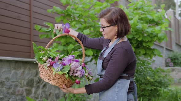 Woman Gardener Florist in Garden with Basket of Fresh Plucked Garden Spring Flowers alt