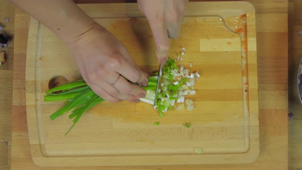 Woman Chopping Scallions Fresh Onion at Wooden Kitchen Table
