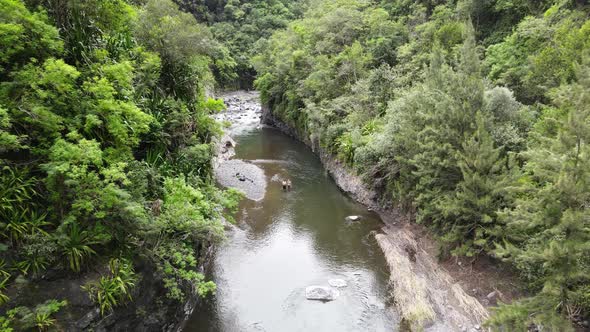 Drone footage of a river in a green canyon with two people in the water in the Cirque of Mafate on t alt