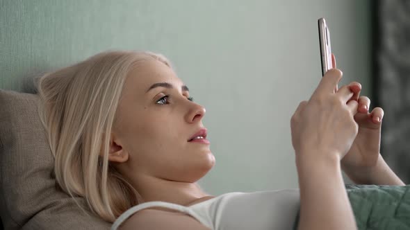 Relaxed Young Woman Using Smart Phone Surfing Social Media Checking News Playing Mobile Games or alt