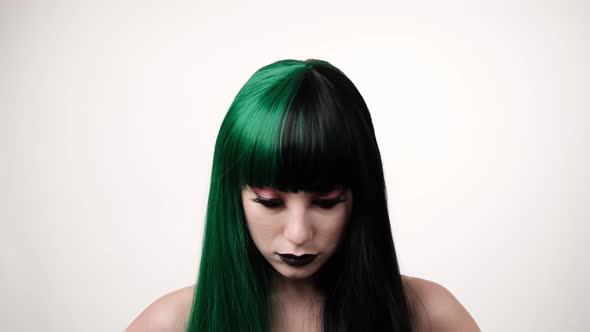 portrait of woman with a green black hair wig straightens long hair alt