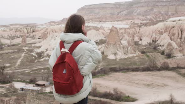 Rear View of Teenage Tourist Girl with Brown Backpack Looking Around Rose Valley and Enjoy Fairytale