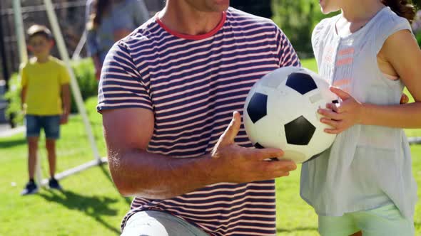 Father assisting daughter to play football alt