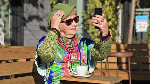 Senior woman takes a selfie on the phone and drinks coffee