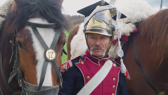 Portrait of a Adult Male Hussar in Medieval Costume a Soldier Standing Next to a Horse in a Field alt