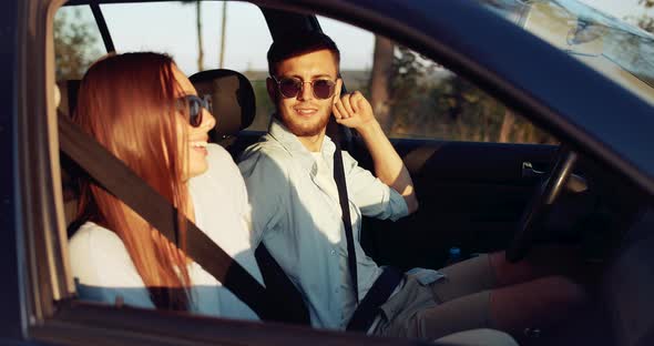 Happy Couple Fastening Seat Belts Sunset