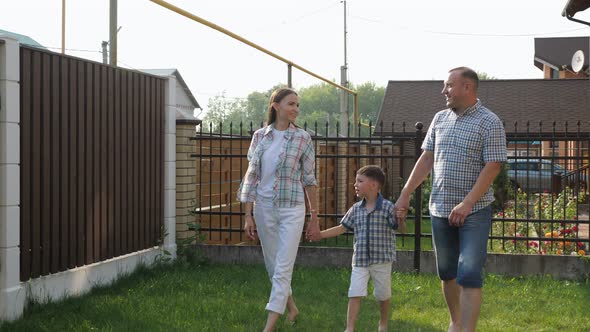 Father and Pretty Mother Hold Happy Little Boy Hands alt