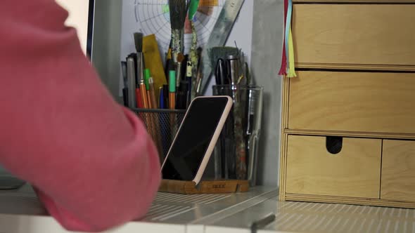 A Woman Works at a Desktop a Computer a Mobile Phone Pencils Pens are Nearby