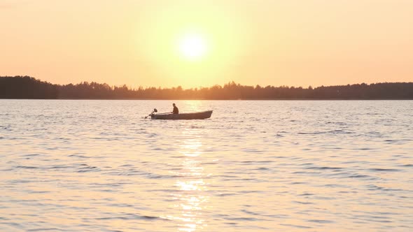 Man sailing in a boat at sunset
