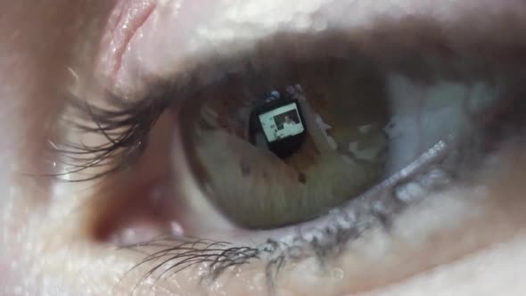 Macro close up, reflection of screen in females eye watching online video alt