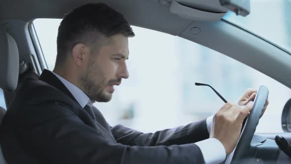 Tired Man in Car Putting Off Glasses and Rubbing Tensioned Eyes, Overworking