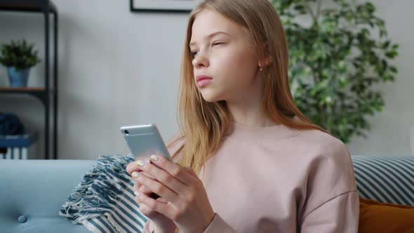 Slow Motion of Serious Teen Child Using Smartphone Messaging Indoors in Apartment alt