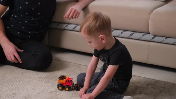 Little Boy is Playing with His Father While His Mother Works Using a Notebook alt