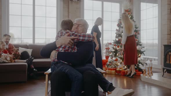 Grandad Hugging His Grandson Sitting on a Chair at Christmas Eve alt