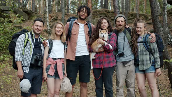 Slow Motion Portrait of Happy Young People Friends Smiling Standing in Summer Forest with Cute Shiba alt