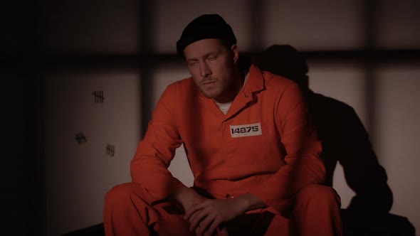 Imprisoned Man Sitting in Cell, Red Light Blinking Fight and Riot Risk in Prison alt