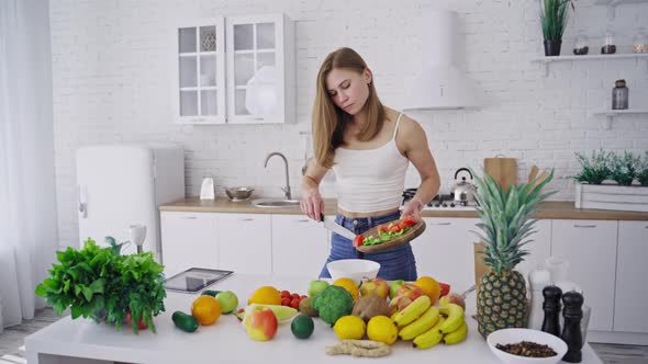 Young pretty woman preparing tasty salad on the modern kitchen alt