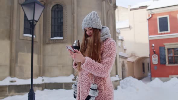 Traveler Woman Holding Mobile Phone Chatting with Friends and Family Drinking Hot Drink Tea alt
