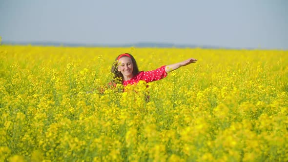 Girl Walks Across the Field with Canola Flowers alt