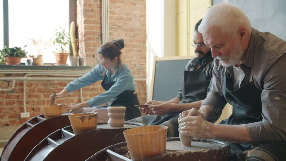 Men and Woman Working with Pottery Wheel Making Pots During Master Class for Adults alt