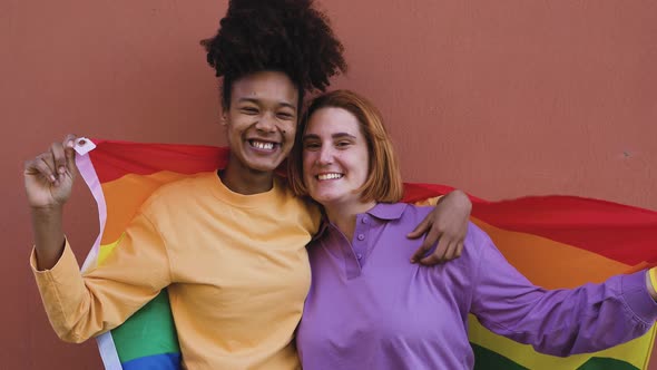 Happy gay couple celebrating pride holding rainbow flag outdoor - Lgbt and love concept alt