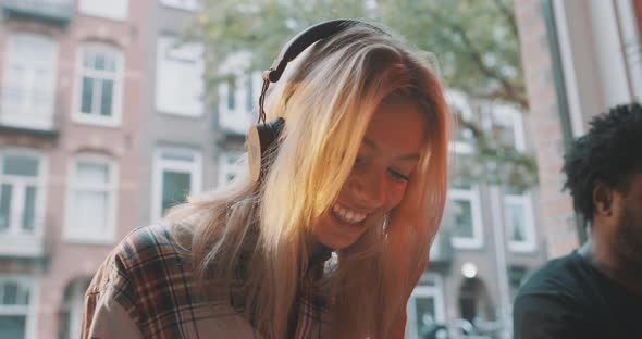 Woman wearing headphones drawing and talking to a friend alt