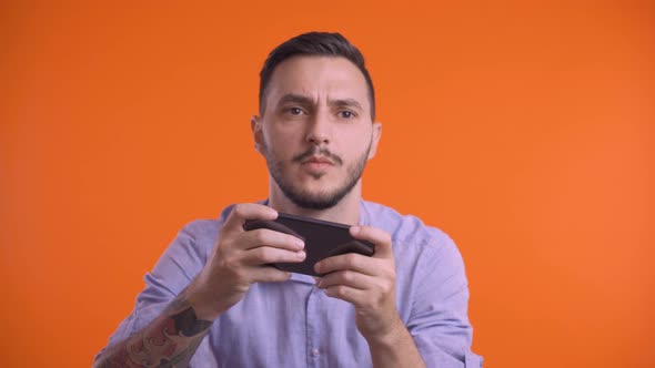 Young Man Playing on Smartphone with Both Hands, Moving Sideways. Front View, Studio Shot alt