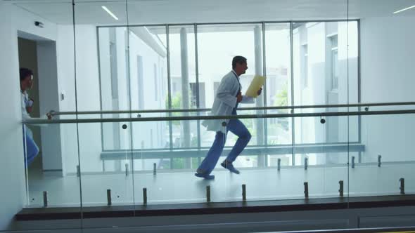 Male and female doctors running in the corridor at hospital alt
