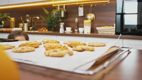 Little Child is Running Up to the Table Taking Just Baked Cookie with Nuts From Baking Sheet and alt