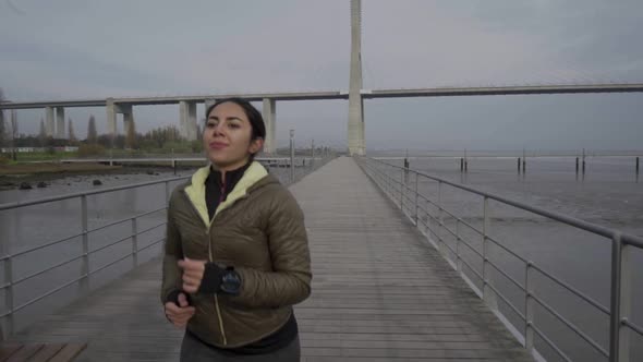 Smiling Hindu Woman Running on Wooden Pier on Seaside. alt