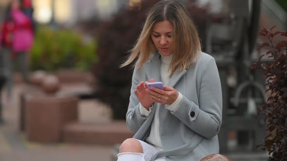 girl typing by mobile phone on city street