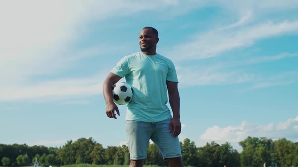 African Guy Holding Football in Hand in Nature alt
