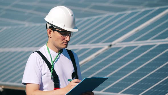 A Man Is Doing an Inspection of Outdoors Solar Panels. Renewable Energy, Solar Plant, Green alt