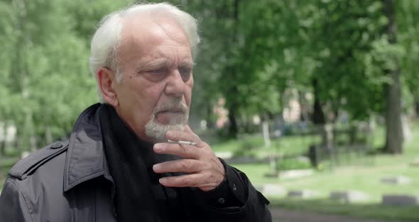 Sad Old Gray Haired Man Smokes Cigarette on the Cemetery Sorrow and Sadness About Lost of Close alt