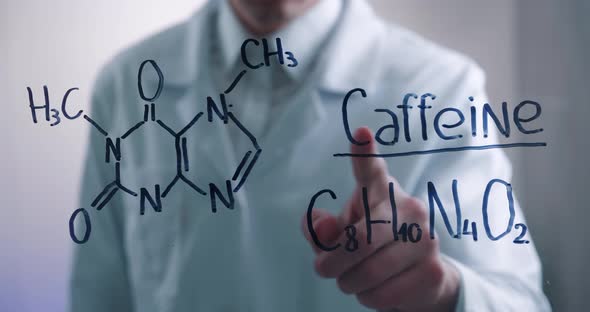 Man Scientist Thinks Over the Solution of Chemical Formula of Caffeine Drawn on a Glass Board in a alt