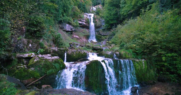 Moody Giessbach waterfall view at morning, splashing on rocks inside lush green forest in Brienz Swi alt